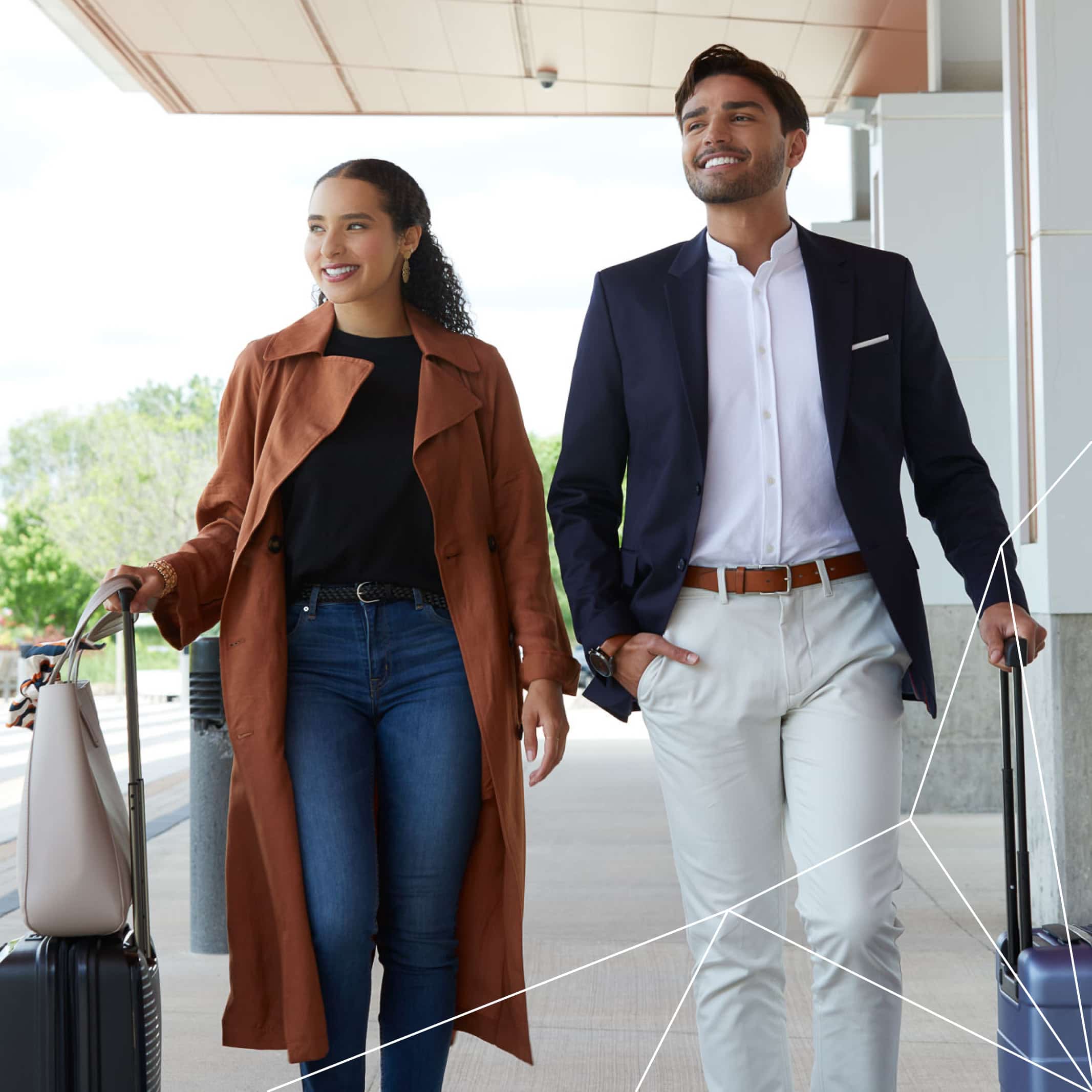 Two professionals walk through modern airport terminal with luggage, dressed in business casual attire.