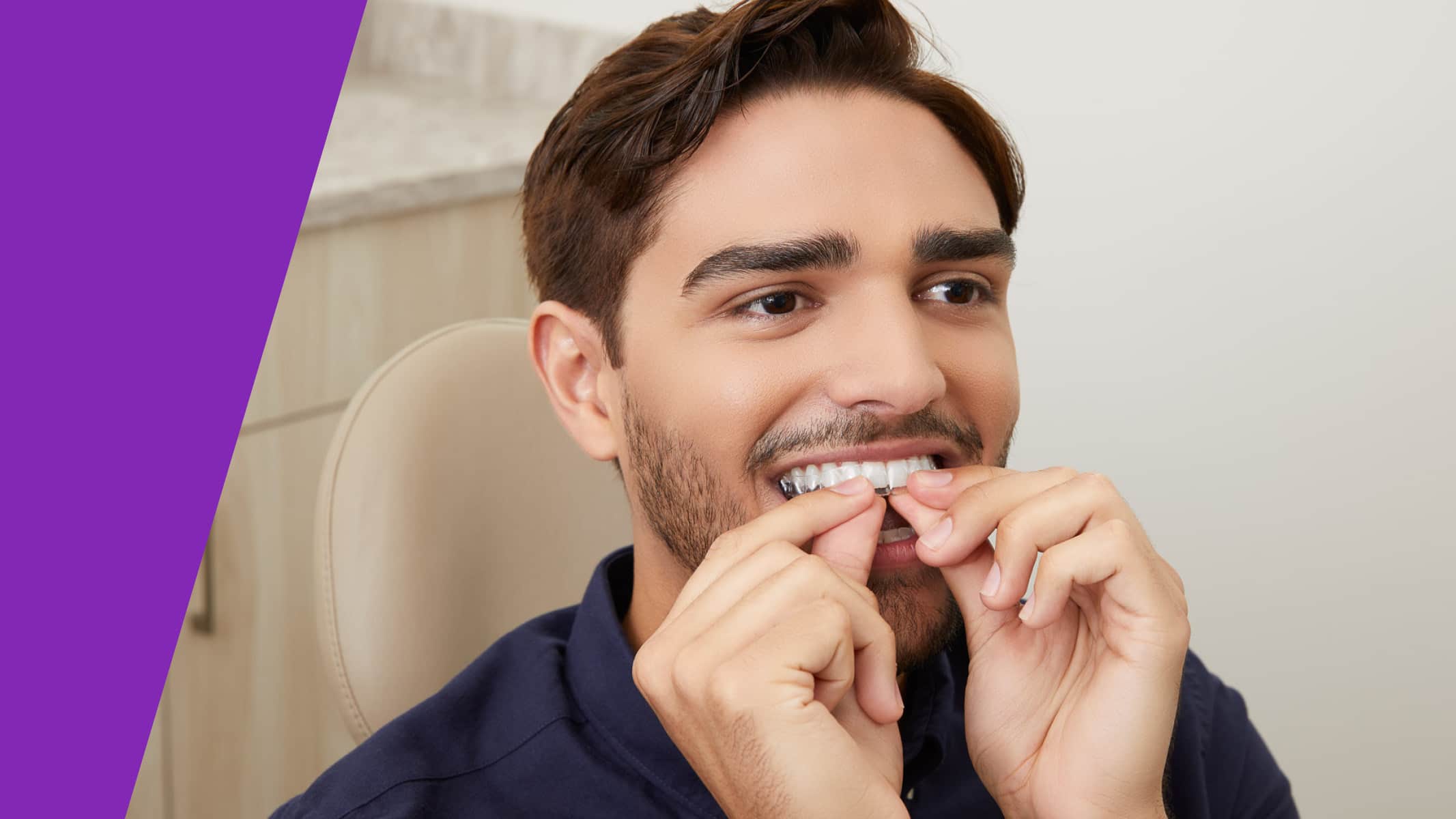 Man inserting clear aligners into his mouth in a dental office setting.