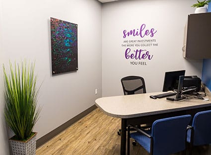 Modern orthodontics office with desk, computers, motivational wall text, and professional workspace decor.
