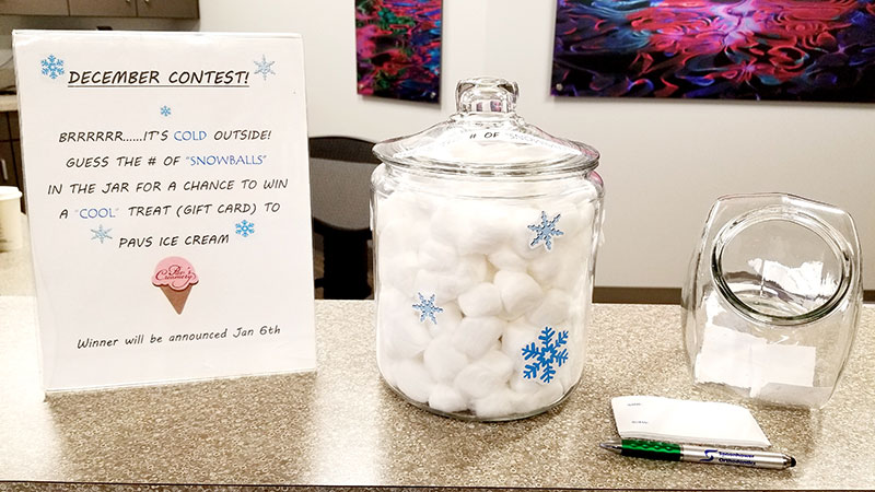 Orthodontic office display featuring winter-themed candle, thank you card, and dental materials on desk.