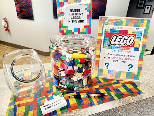 LEGO-themed orthodontic office display with colorful bricks in jar and promotional materials on counter.