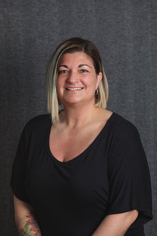 Professional headshot of woman smiling against gray background, likely orthodontics staff member.