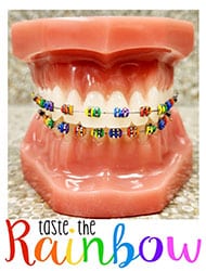 Dental model displaying rainbow-colored orthodontic braces with "taste the rainbow" text overlay.