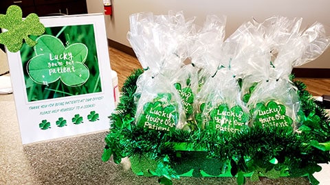 Green orthodontic promotional items and packaged merchandise displayed on counter at dental office.