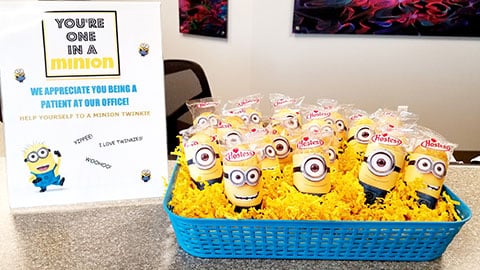 Blue basket filled with yellow Minion plush toys in orthodontic office waiting area.